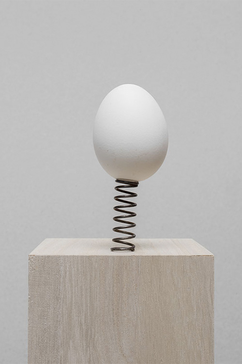 een wit ei op een metalen veer op een sokkel © Hans van Asch