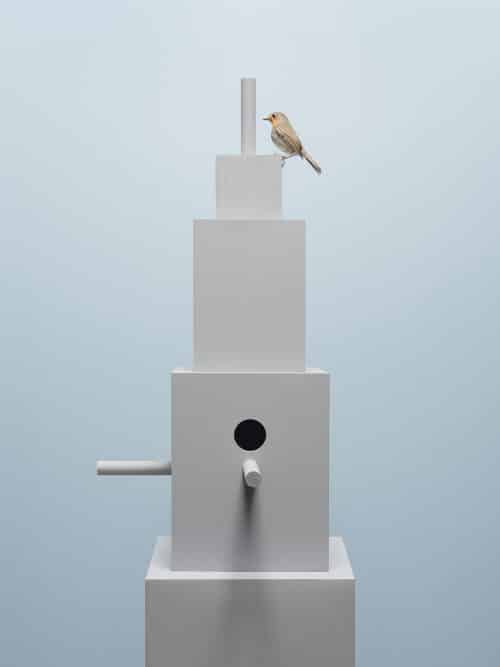 Grijze vogelhuis toren met hemelsblauwe achtergrond met een roodborstje op de top van het gebouw | © Hans van Asch